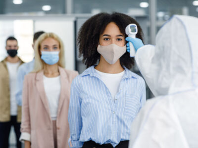 Checking temperature of multiracial workers in protective masks with infrared thermometer, cpap covid covid19
